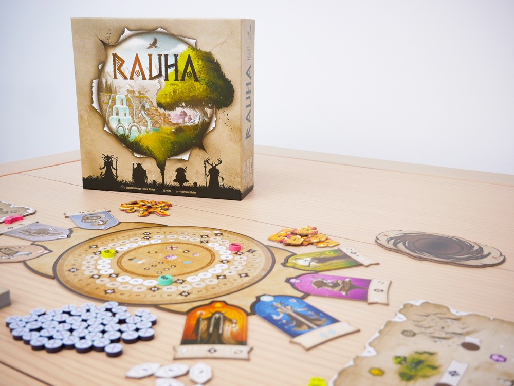 Caja del juego Rauha junto al tablero circular y componentes sobre mesa