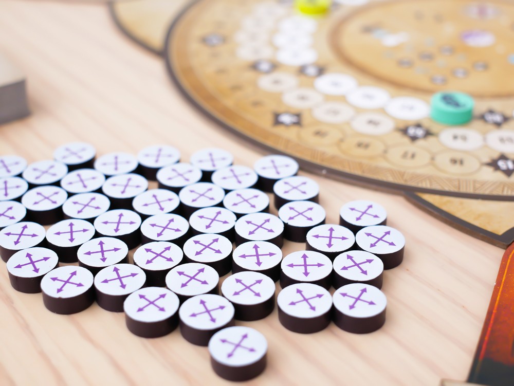 Tokens circulares Rauha con símbolo de flechas cardinales sobre mesa