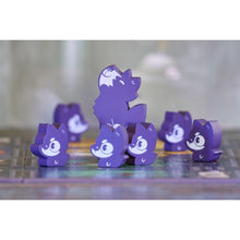 Fichas de madera violetas de monstruos sonrientes y lobo sobre el tablero de juego
