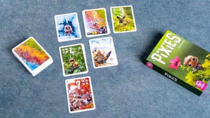 Juego de cartas Pixies vista superior con caja y cartas de bosque mágico