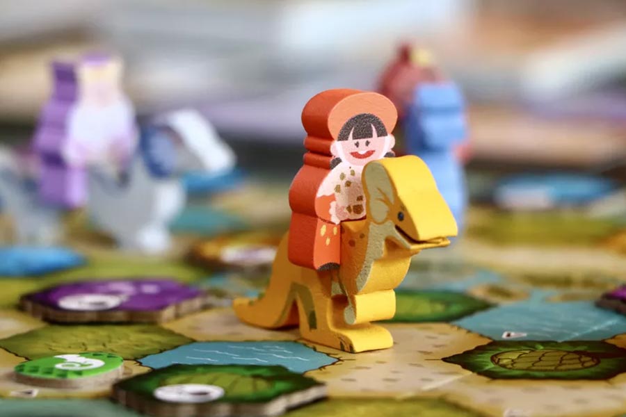 Figura de capitán naranja montado en criatura reptiliana amarilla sobre el tablero de juego