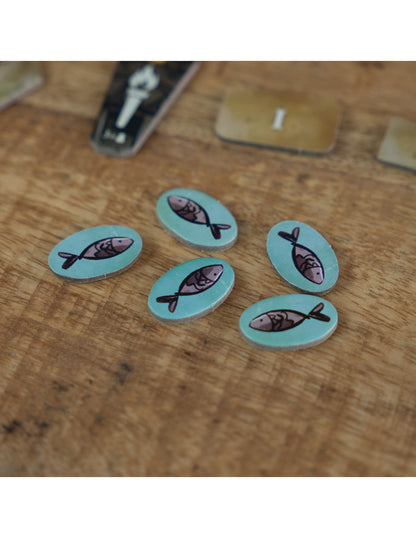 Fichas ovaladas de madera con ilustraciones de peces del juego El Pantano de Feya
