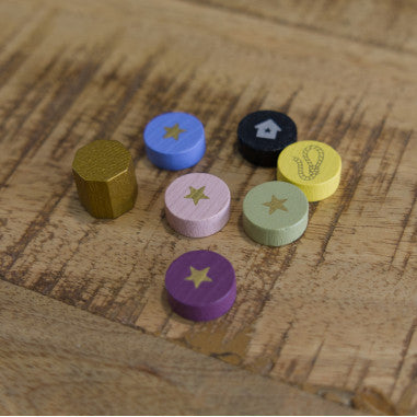 Tokens de madera coloridos del juego Molly House con formas geométricas e iconos